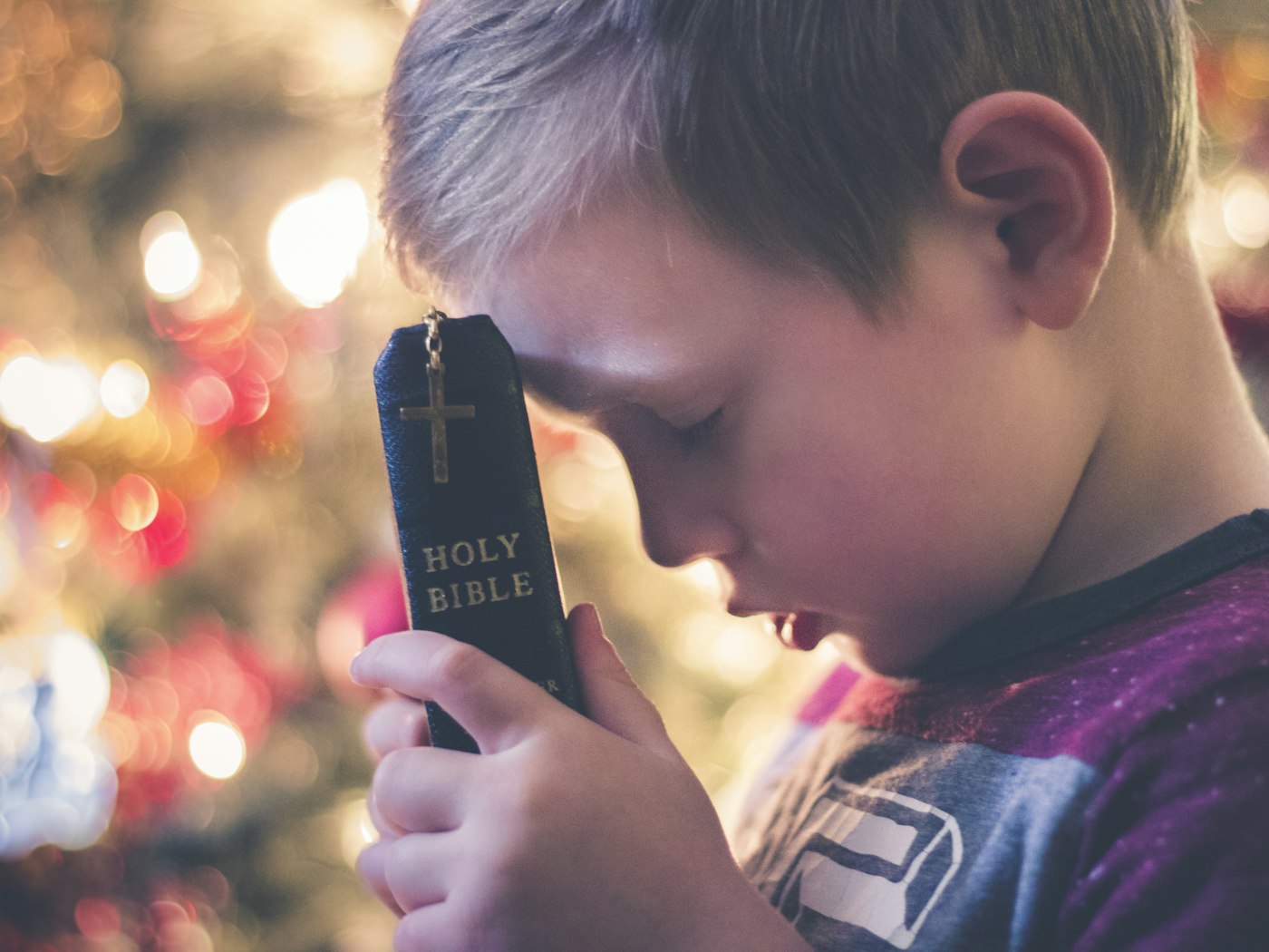 A young boy holding an open Bible in his hands