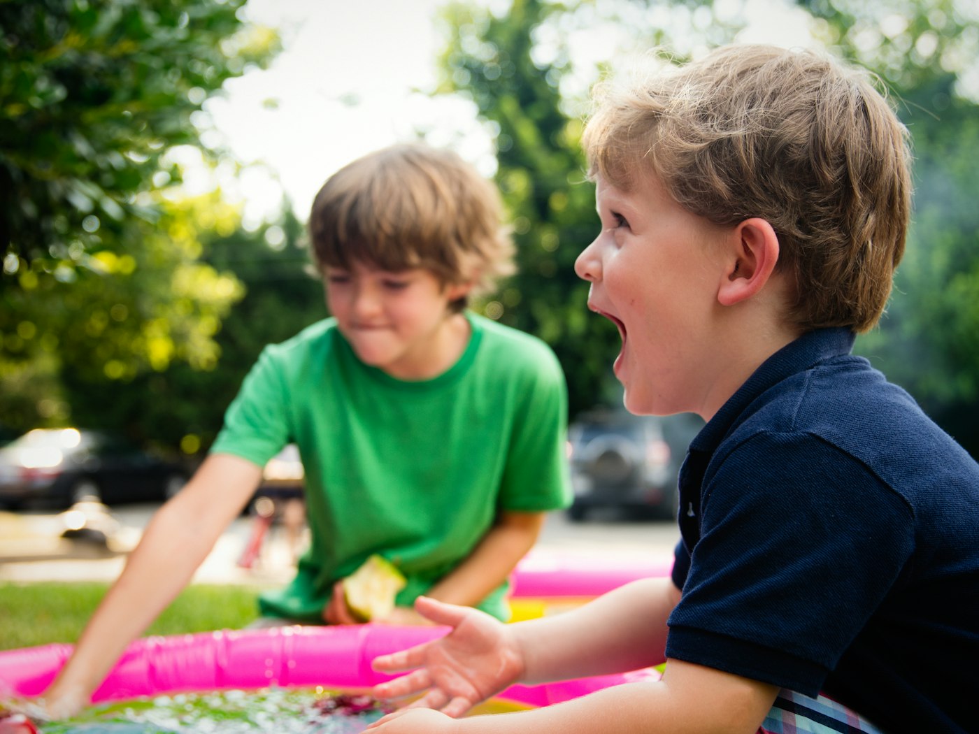 Two elementary-age boys laughing and shouting together outdoors