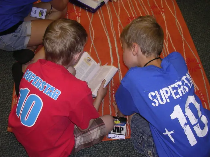 Children opening their own Bibles together during a Go Fish VBS session